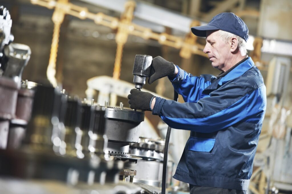 adult experienced industrial worker during heavy industry machinery assembling on production line manufacturing workshop